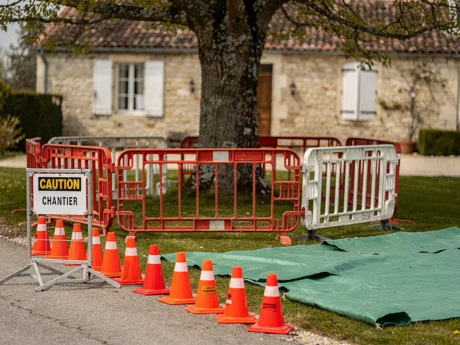 Zone de chantier sécurisée avec barrières, cônes et bâches de protection